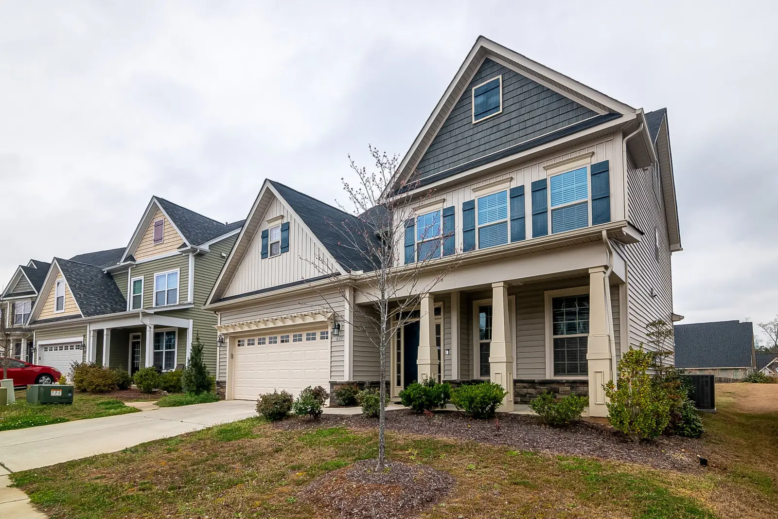 Two-story home with gray lap siding, shake-style gable accents and a covered front porch