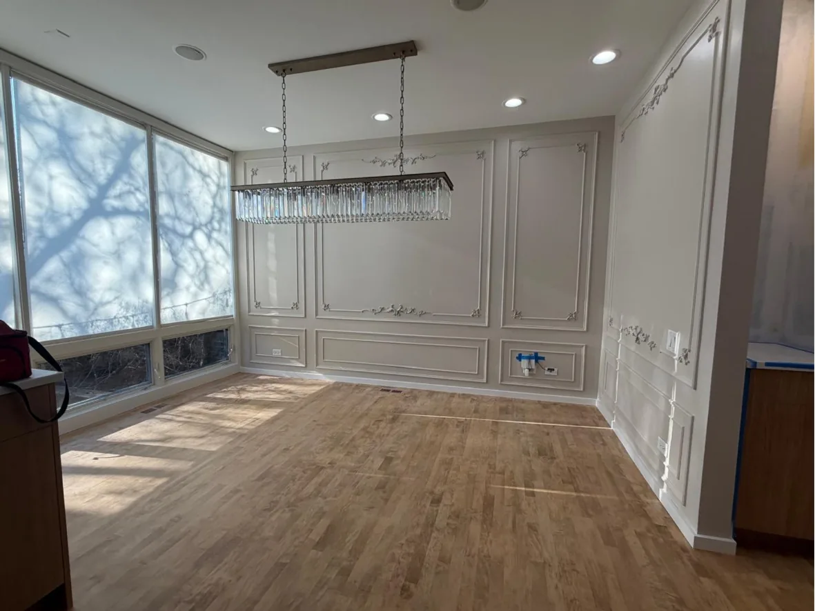 Dining room with applied wall molding and rosette detail, a crystal linear chandelier and light hardwood flooring